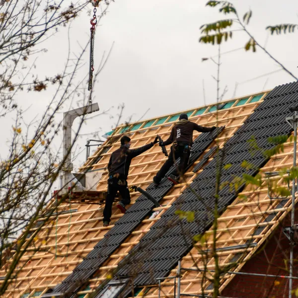 Dachdecker verlegt Ziegel auf einem Steildach